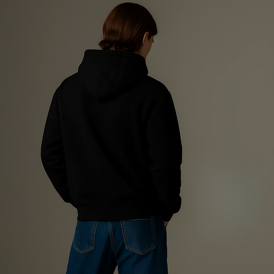 Person wearing a black hoodie and blue jeans against a plain background